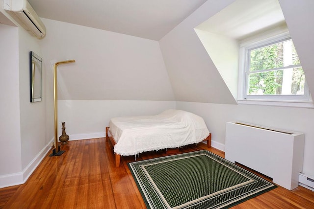 21 Hereford Rd, Great Neck, NY 11020 - bedroom with an AC wall unit, radiator, wood finished floors, baseboards, and lofted ceiling
