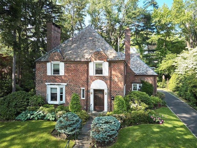 21 Hereford Rd, Great Neck, NY 11020 - view of front of property featuring a high end roof, a chimney, brick siding, and a front lawn