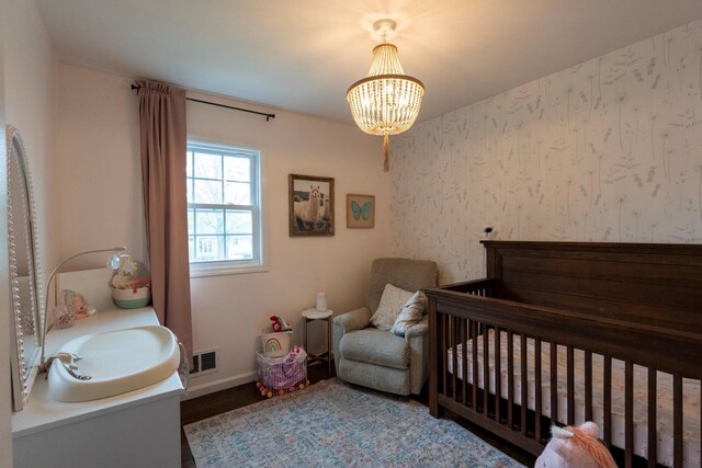 bedroom featuring a chandelier, baseboards, wood finished floors, and wallpapered walls