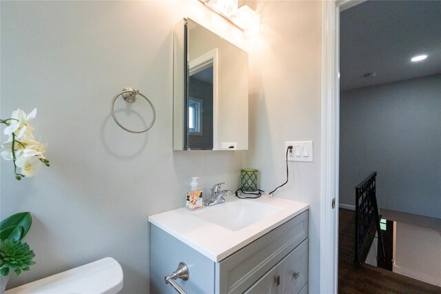 half bath featuring vanity, toilet, and wood finished floors