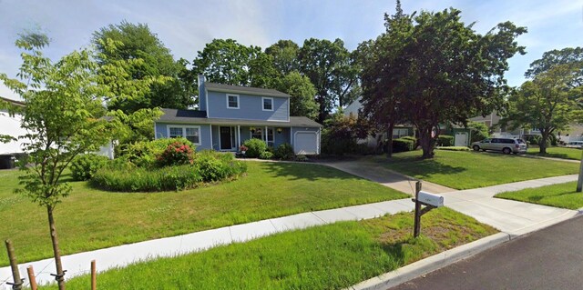 traditional-style home with a garage, a front yard, driveway, and a chimney