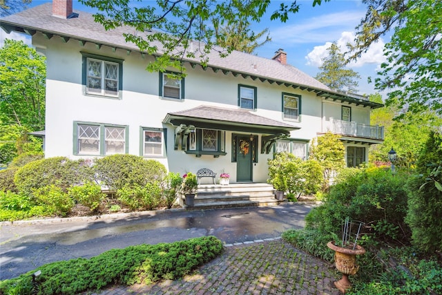 17 The Intervale, Roslyn Estates, NY 11576 - view of front facade with a chimney, stucco siding, and roof with shingles