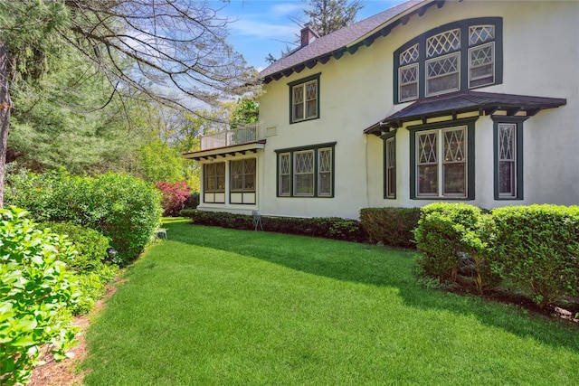 17 The Intervale, Roslyn Estates, NY 11576 - view of side of home featuring stucco siding, a chimney, a balcony, a yard, and roof with shingles