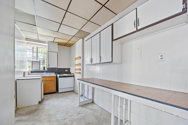 1410 Lincoln Pl, Brooklyn, NY 11213 - kitchen with white gas range, a sink, light countertops, a drop ceiling, and light tile patterned flooring