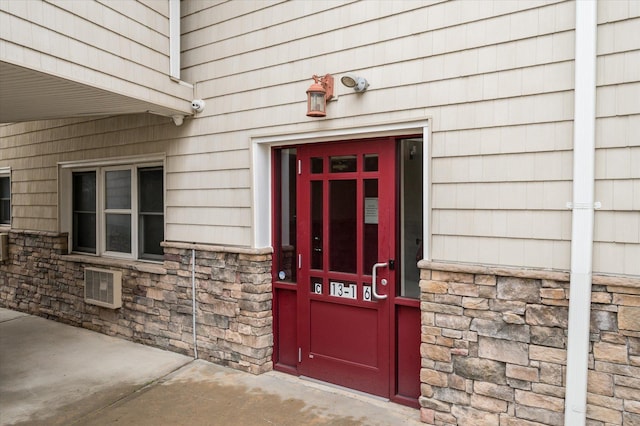 doorway to property with stone siding and a security system