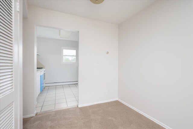 spare room with light carpet, baseboards, a baseboard radiator, and light tile patterned flooring