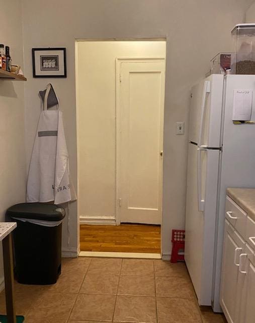 kitchen featuring light tile patterned flooring, freestanding refrigerator, and light countertops