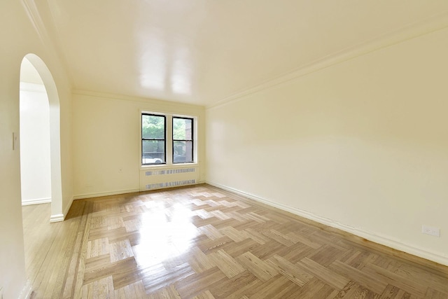 empty room with arched walkways, radiator, crown molding, and baseboards