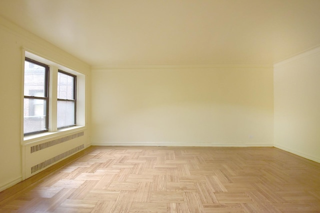 unfurnished room with radiator heating unit and baseboards
