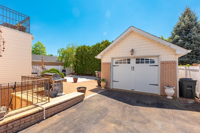 detached garage featuring driveway and fence
