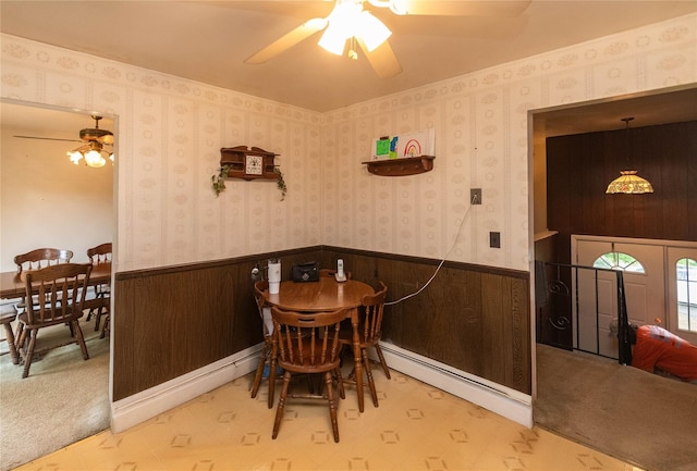 3042 Gomer St, Yorktown Heights, NY 10598 - dining area featuring ceiling fan, a baseboard heating unit, a wainscoted wall, and wood walls