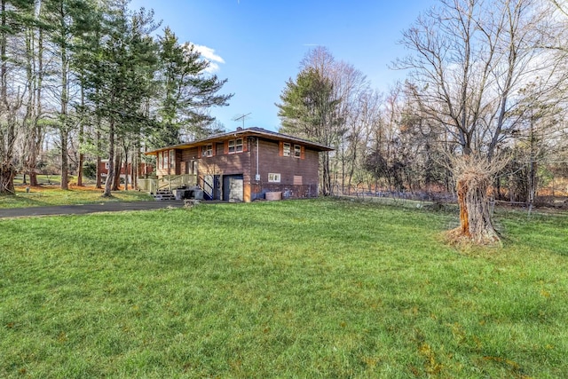 view of green lawn with driveway and a garage