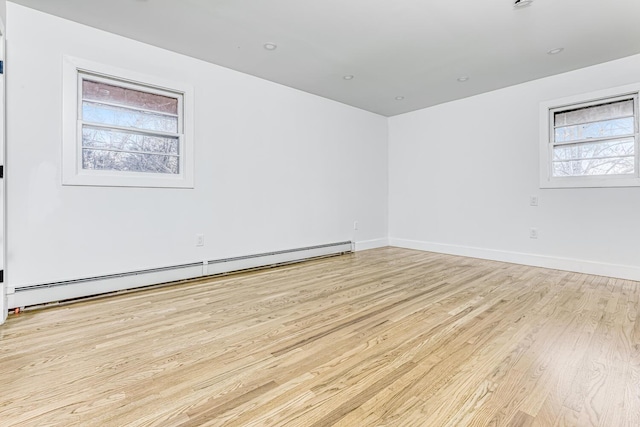 empty room with baseboard heating, light wood-style flooring, and baseboards