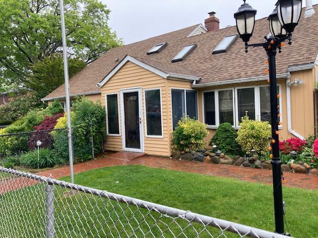 rear view of property featuring roof with shingles and a chimney