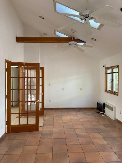 spare room with ceiling fan, radiator heating unit, baseboards, french doors, and high vaulted ceiling