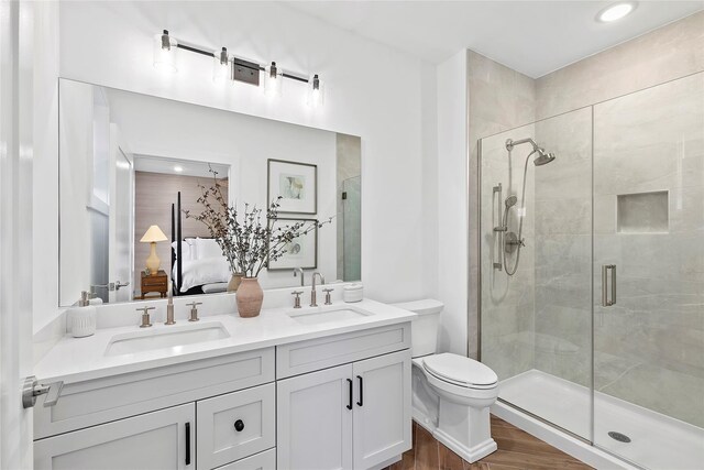 full bath featuring a stall shower, wood finished floors, double vanity, toilet, and ensuite bath
