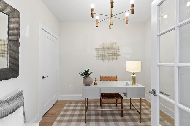 office space with a chandelier, wood finished floors, and baseboards