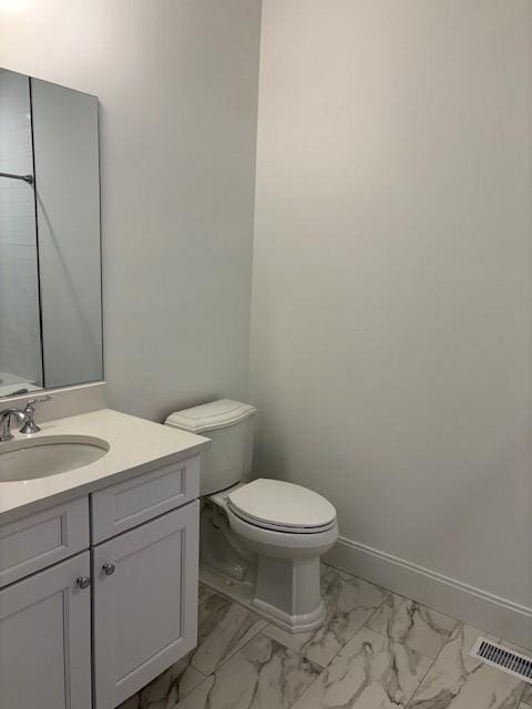 bathroom with marble look tile flooring, toilet, vanity, and baseboards