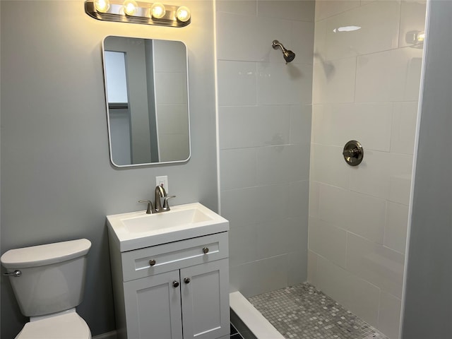 bathroom with toilet, vanity, and a tile shower