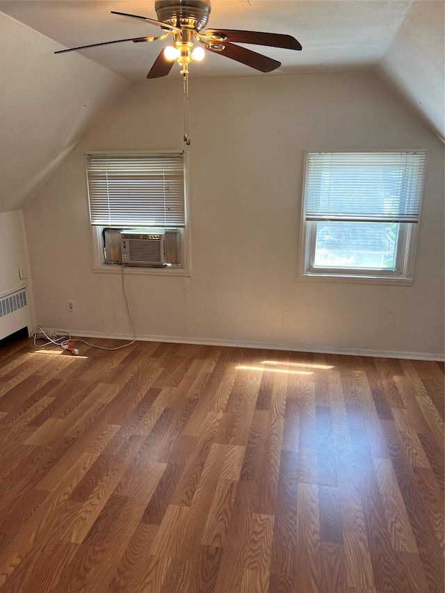 bonus room with vaulted ceiling, wood finished floors, radiator heating unit, ceiling fan, and cooling unit