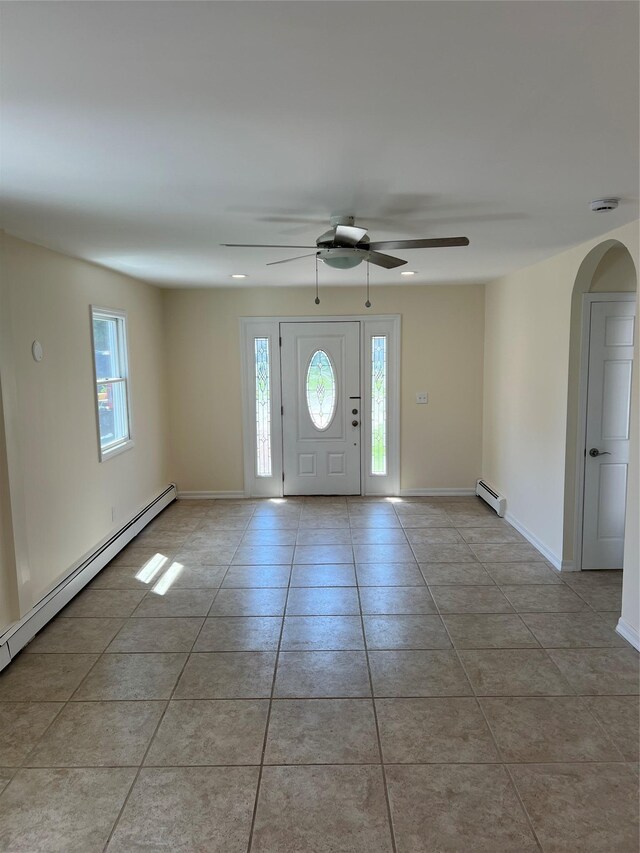 foyer with arched walkways, baseboard heating, a ceiling fan, and tile patterned floors