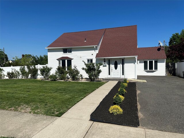 new england style home with asphalt driveway and a shingled roof