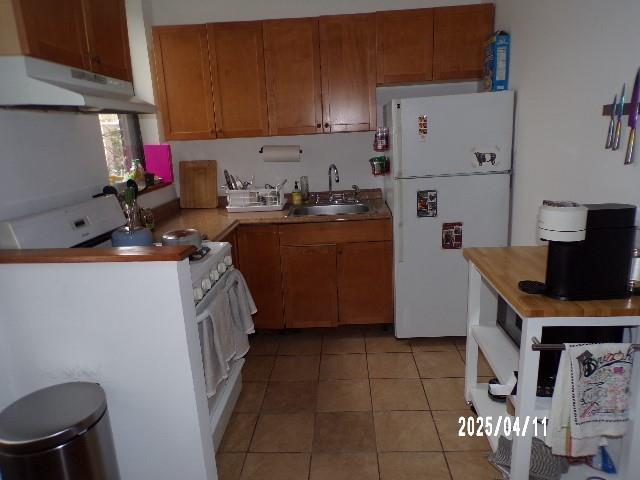 173 Quincy St, Brooklyn, NY 11216 - kitchen with white appliances, under cabinet range hood, a sink, and brown cabinetry