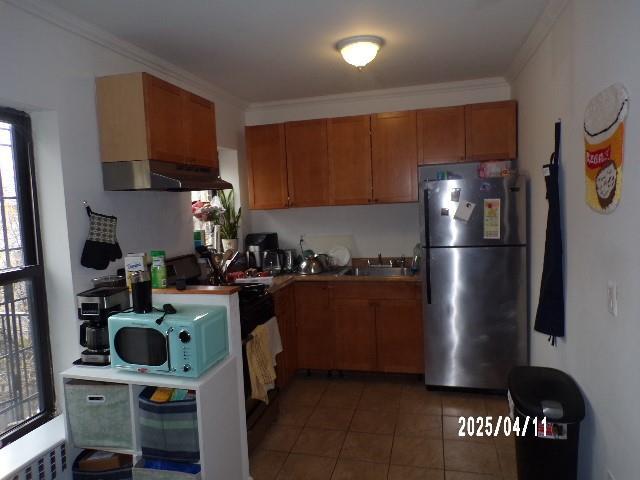 173 Quincy St, Brooklyn, NY 11216 - kitchen with freestanding refrigerator, white microwave, a sink, under cabinet range hood, and brown cabinets