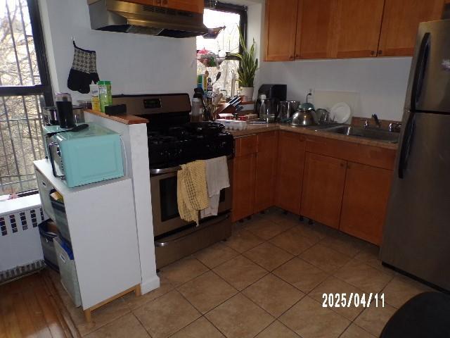 173 Quincy St, Brooklyn, NY 11216 - kitchen with under cabinet range hood, freestanding refrigerator, stainless steel gas range oven, radiator, and a sink