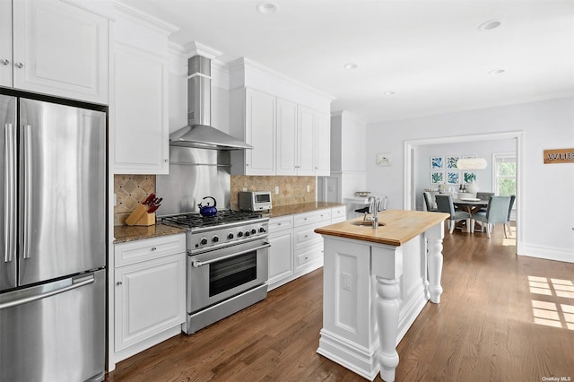 394 Mill Rd, Westhampton, NY 11977 - kitchen with stainless steel appliances, wooden counters, wall chimney exhaust hood, white cabinets, and recessed lighting