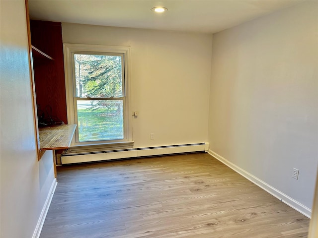 spare room featuring baseboard heating, light wood-style flooring, baseboards, and recessed lighting