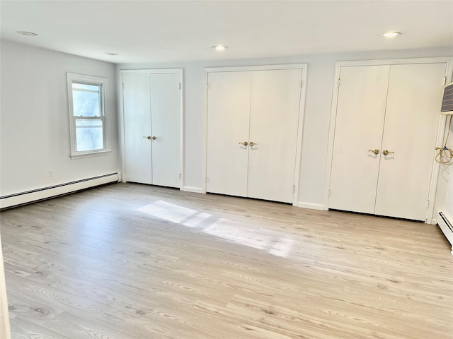 unfurnished bedroom featuring multiple closets, light wood-style flooring, a baseboard heating unit, recessed lighting, and baseboards
