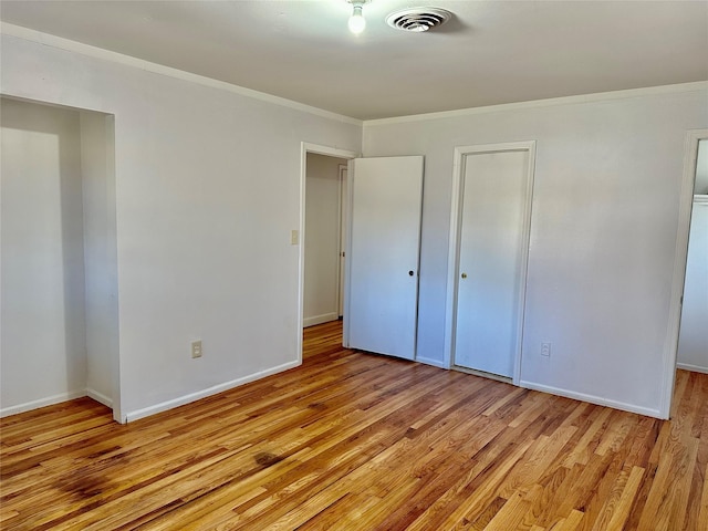 unfurnished bedroom with light wood-style floors, crown molding, baseboards, and a closet