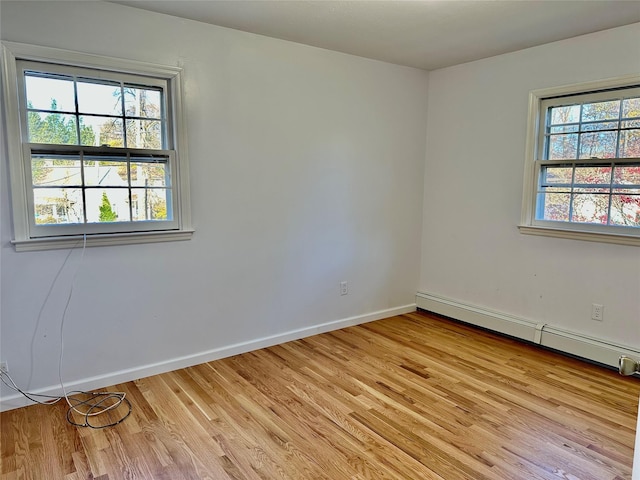 spare room with healthy amount of natural light, light wood finished floors, and a baseboard radiator