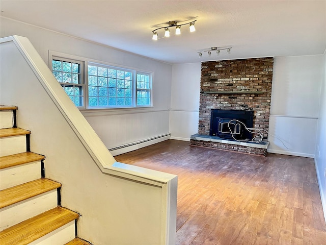 unfurnished living room featuring a baseboard heating unit, wood finished floors, stairway, baseboards, and a fireplace