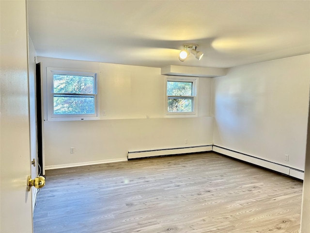 spare room featuring baseboard heating, wood finished floors, and baseboards
