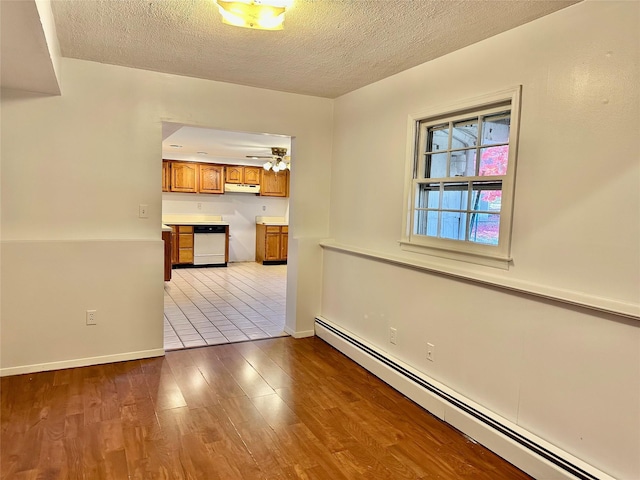 unfurnished room with a baseboard radiator, a textured ceiling, wood finished floors, ceiling fan, and baseboards