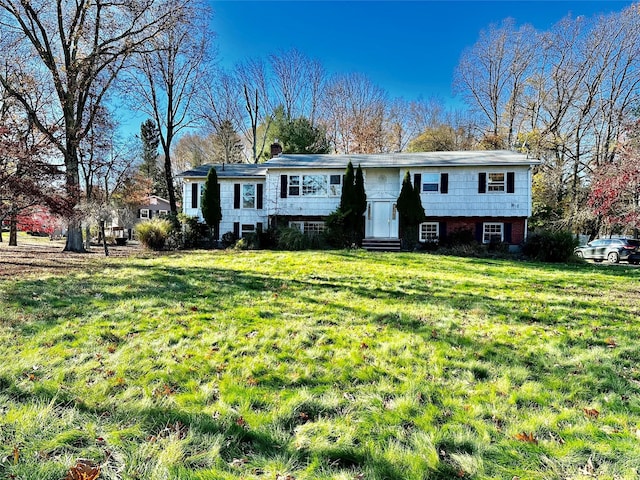 raised ranch with entry steps, a chimney, and a front yard