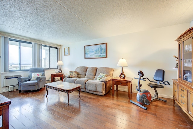 living area featuring hardwood / wood-style floors, a wall mounted air conditioner, and a textured ceiling