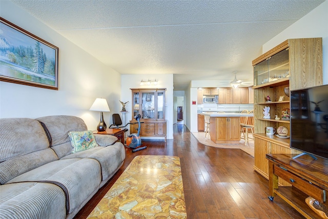 living area with dark wood-style floors, a ceiling fan, and a textured ceiling