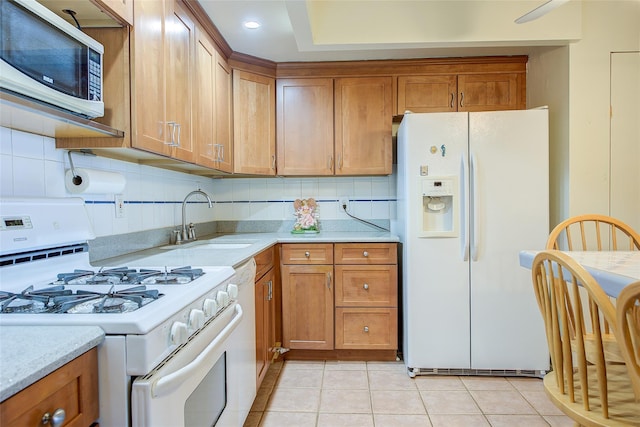 kitchen featuring white appliances, a sink, brown cabinetry, and backsplash