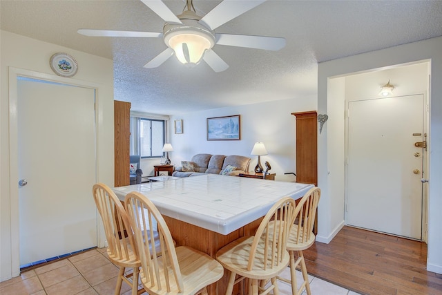 dining area featuring a ceiling fan, a textured ceiling, and light wood-style flooring