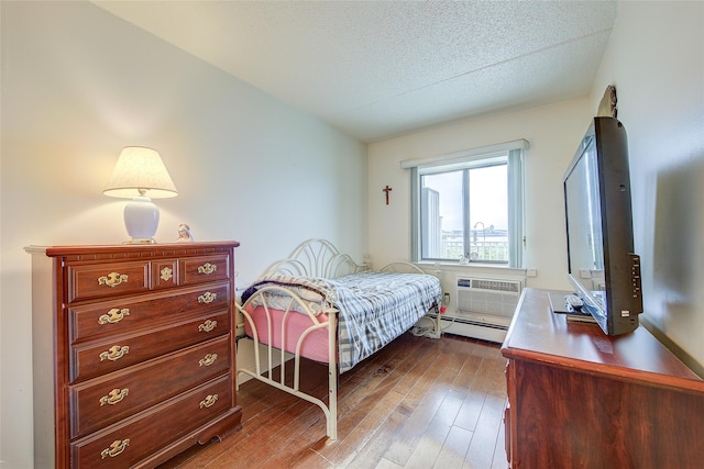 bedroom featuring a baseboard radiator, wood-type flooring, a textured ceiling, and a wall mounted AC