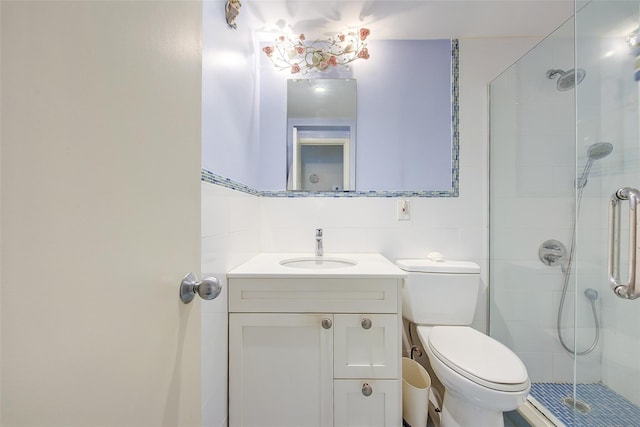 full bathroom with tile walls, a shower stall, vanity, and toilet