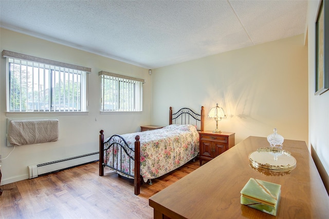 bedroom with baseboard heating, wood finished floors, and a textured ceiling