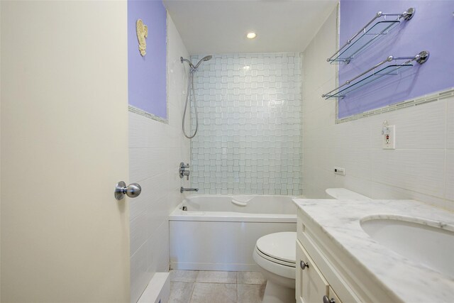 bathroom with tile walls, toilet, tile patterned flooring, vanity, and shower / washtub combination