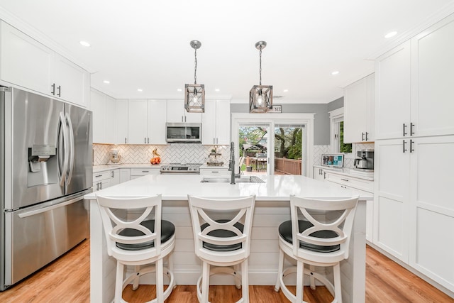 kitchen featuring stainless steel appliances, a sink, tasteful backsplash, light countertops, and white cabinets