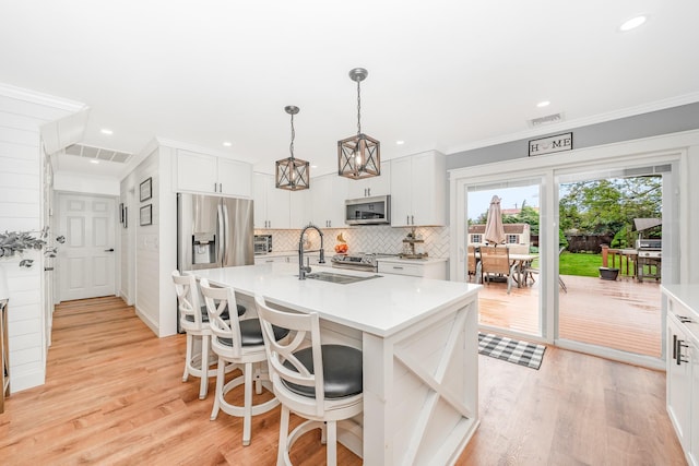 kitchen with stainless steel appliances, light countertops, a sink, light wood-type flooring, and recessed lighting