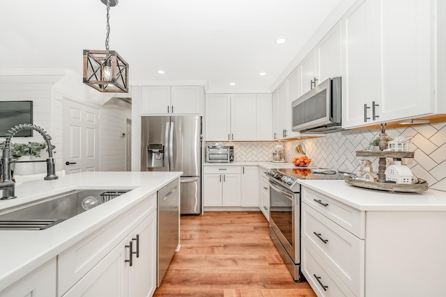 kitchen with stainless steel appliances, a sink, decorative light fixtures, white cabinetry, and recessed lighting