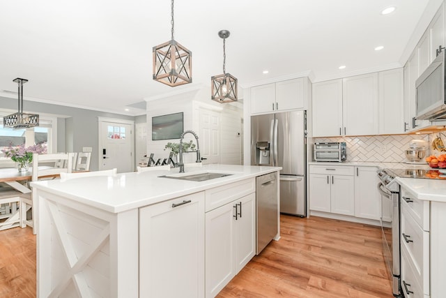 kitchen with stainless steel appliances, a sink, backsplash, an island with sink, and light countertops